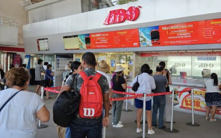 Pasajeros hacen fila en las taquillas de ADO en Cancún.