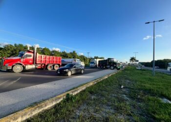 Camiones de carga estacionados en el acotamiento de la carretera federal 307 junto al paso de automóviles
