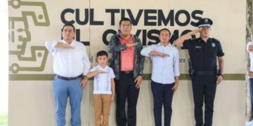 Autoridades de Playa del Carmen y una integrante del Cabildo Infantil rinden honores a la bandera en el programa Cultivemos el Civismo
