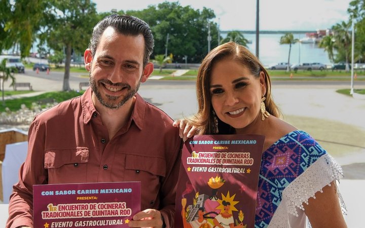 Bernardo Cueto Riestra y Mara Lezama sostienen el cartel del Primer Encuentro de Cocineras Tradicionales de Quintana Roo