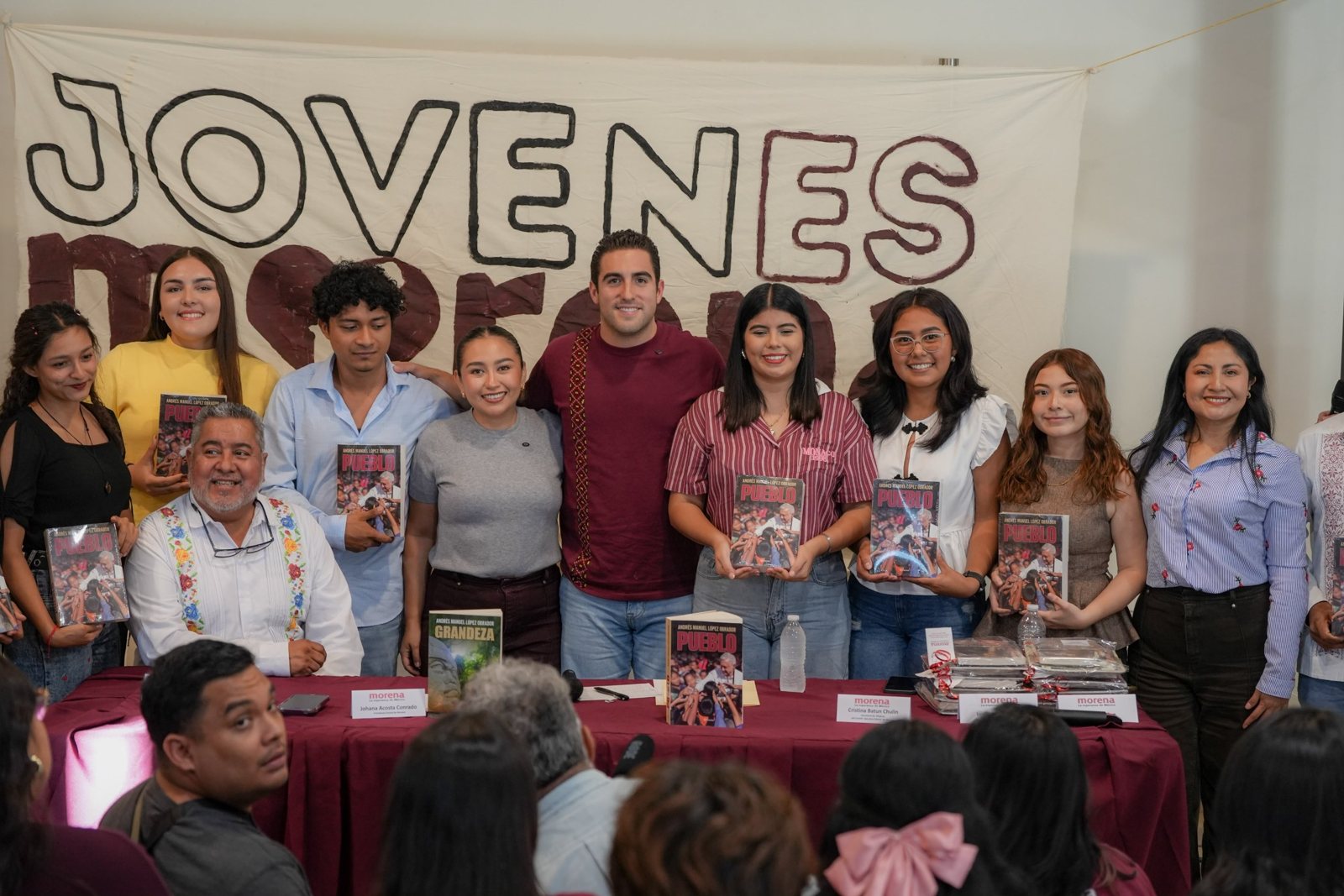 Gino Segura y jóvenes de Morena con el libro Pueblo de Andrés Manuel López Obrador