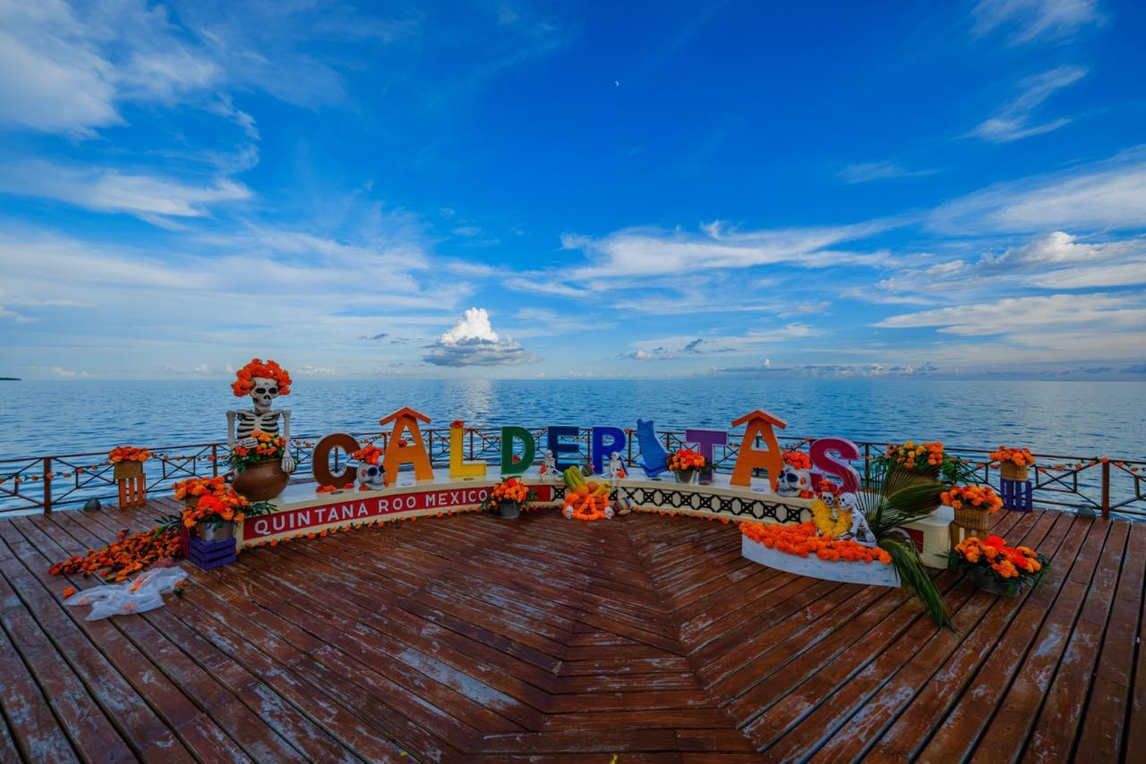 Letras de Calderitas adornadas con flor de cempasúchil frente a la Bahía de Chetumal
