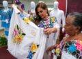 Mara Lezama observa una prenda bordada junto a una artesana durante la premiación en Chetumal