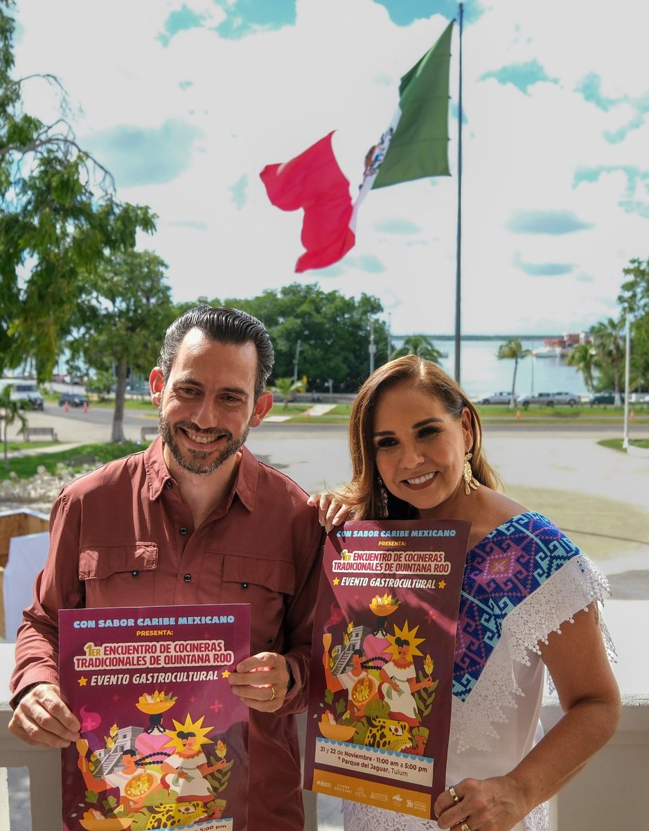 Mara Lezama y Bernardo Cueto con el cartel del encuentro de cocineras tradicionales, con la bahía de Chetumal al fondo