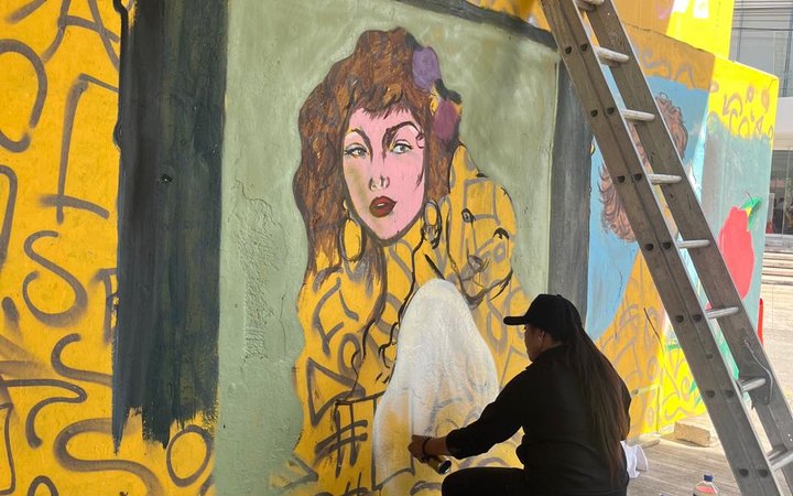 Artista urbana pinta un mural en el muro bajo el puente de López Portillo y Bonampak, en Cancún, donde se exhibía el Museo de los Hampones