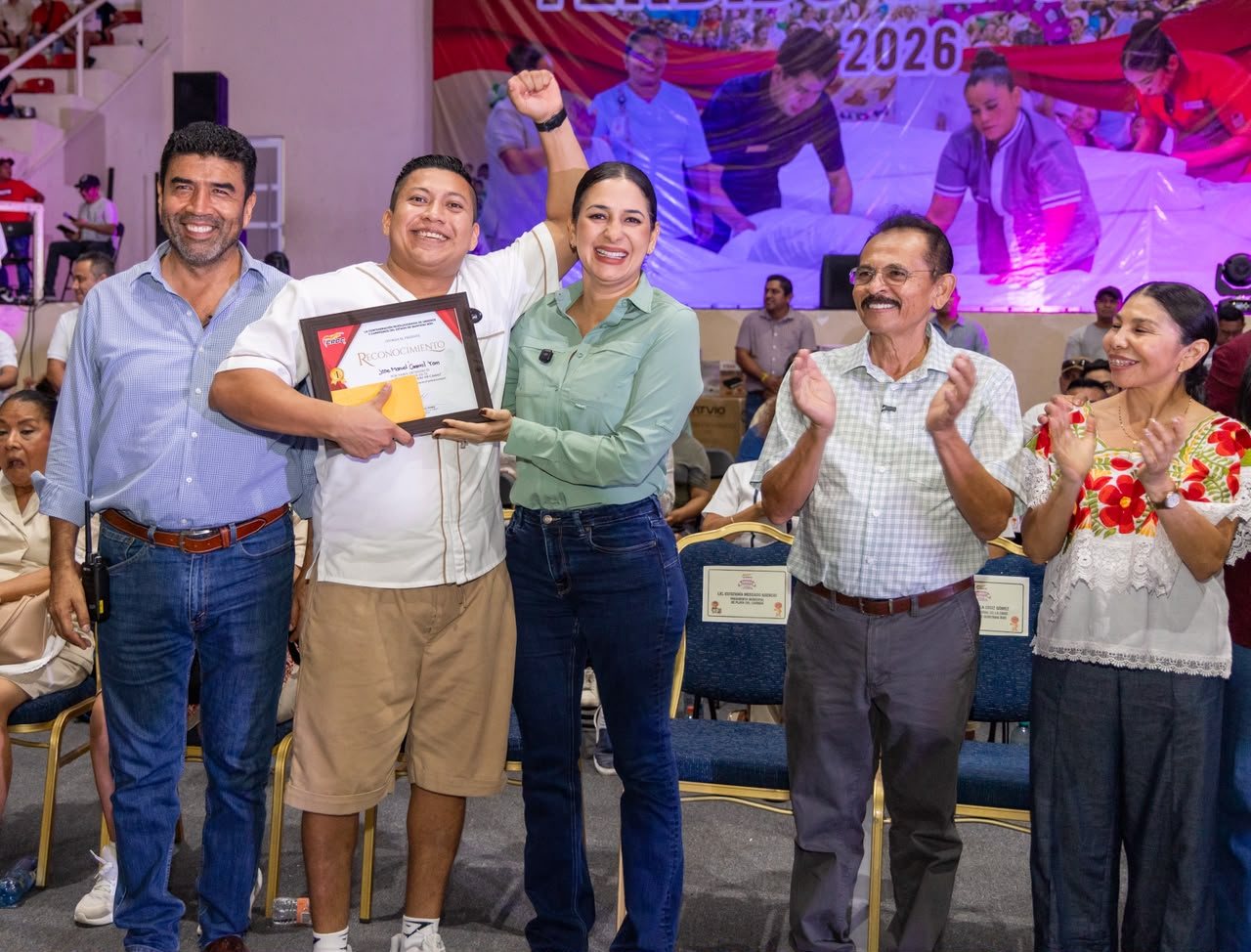 Estefanía Mercado entrega un reconocimiento a un camarista en el Concurso Tendido de Camas