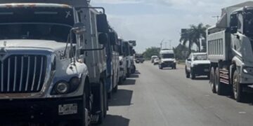 Camiones de transportistas estacionados en un carril de la carretera 307 en Cancún.