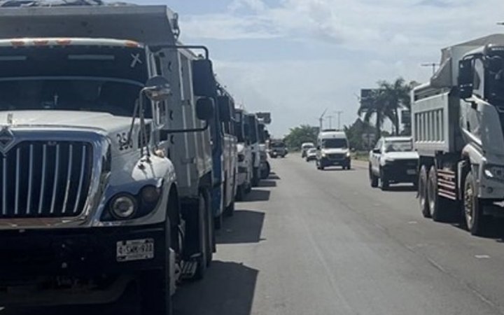 Camiones de transportistas estacionados en un carril de la carretera 307 en Cancún.