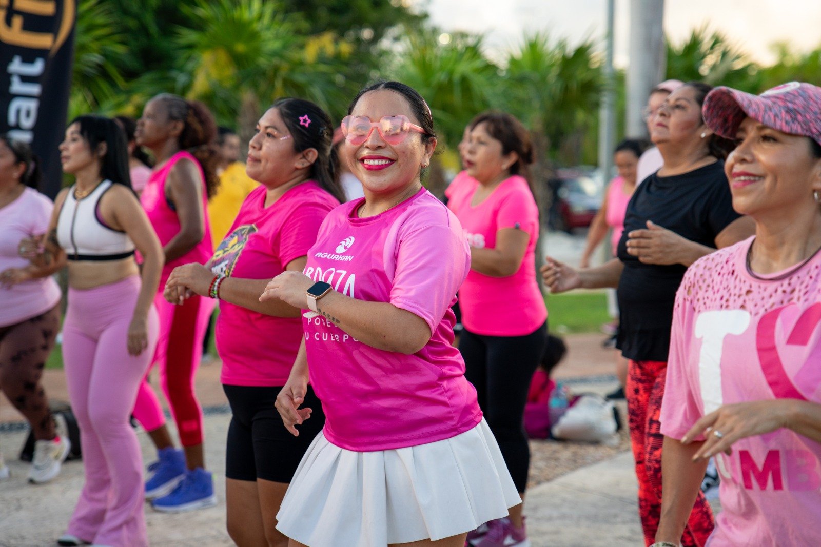 Mujeres bailan con playeras rosas en el Zumbatón Rosa de Aguakan en Cancún